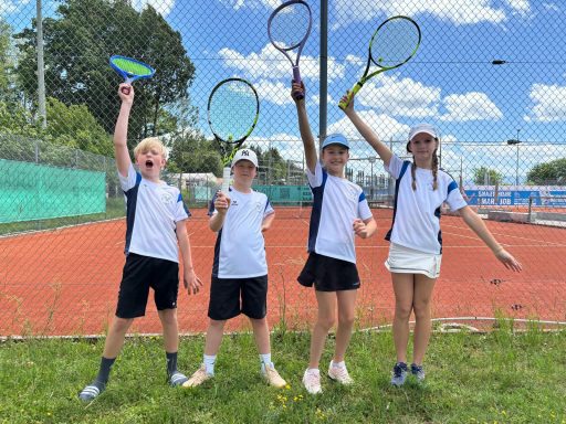 jubelnde Kinder mit Tennisschlägern vor dem Tennisplatz