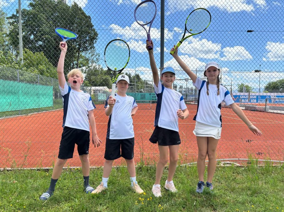 jubelnde Kinder mit Tennisschlägern vor dem Tennisplatz