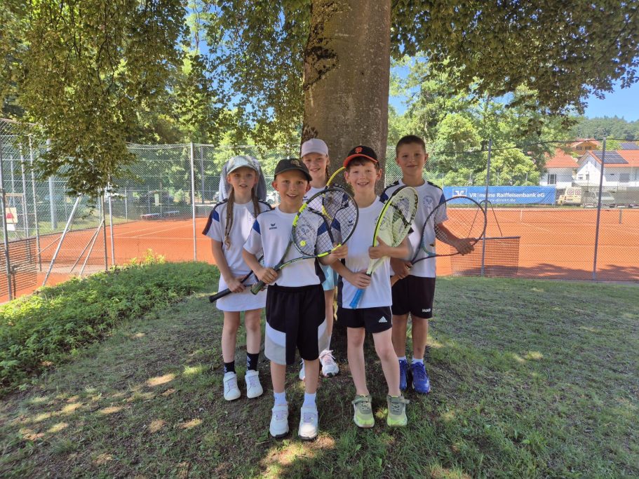 Kinder mit Tennisschlägern unter einem Baum am Tennisplatz